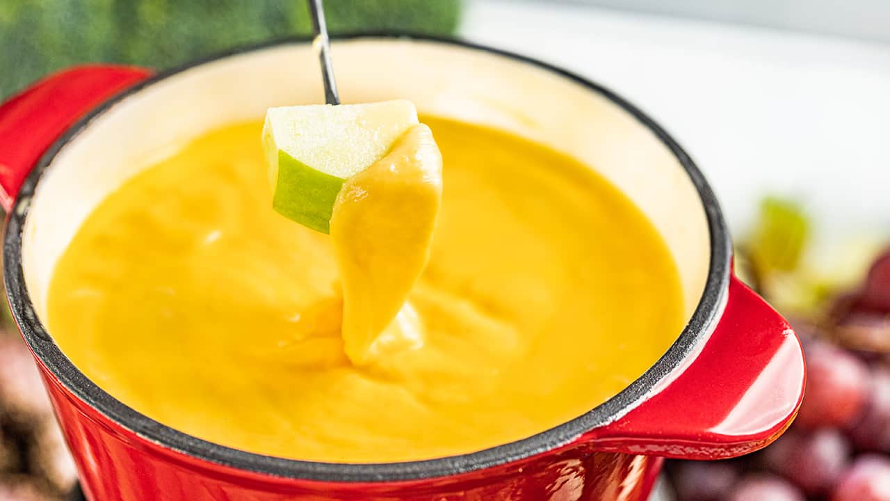 An apple piece dipped in cheese fondue.