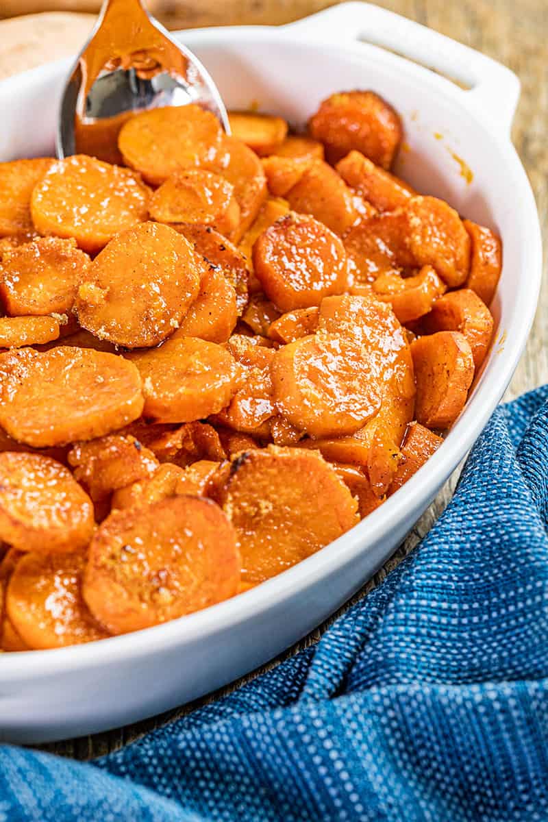 Close up view of candied yams in a white baking dish.