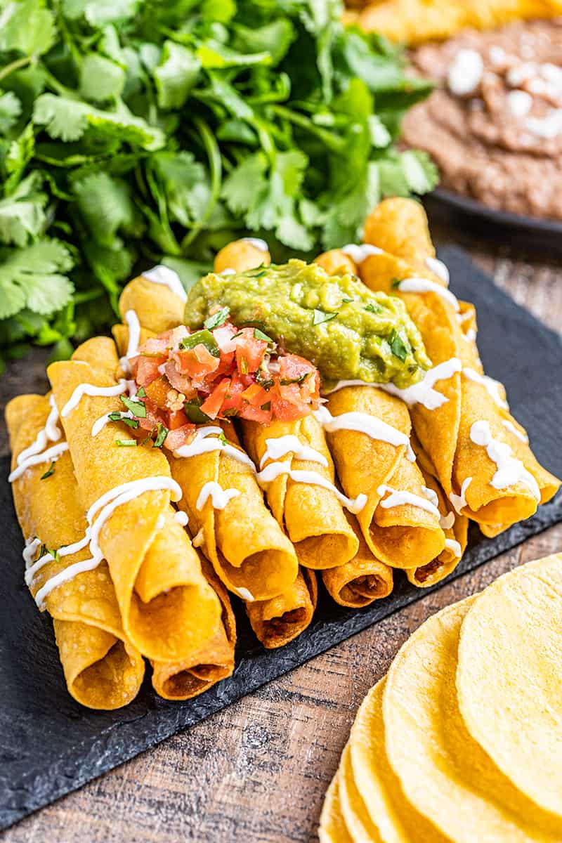 Crispy taquitos with fresh salsa and guacamole on top.