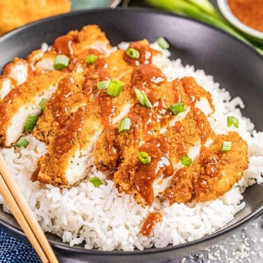 Chicken katsu in a bowl with white rice.