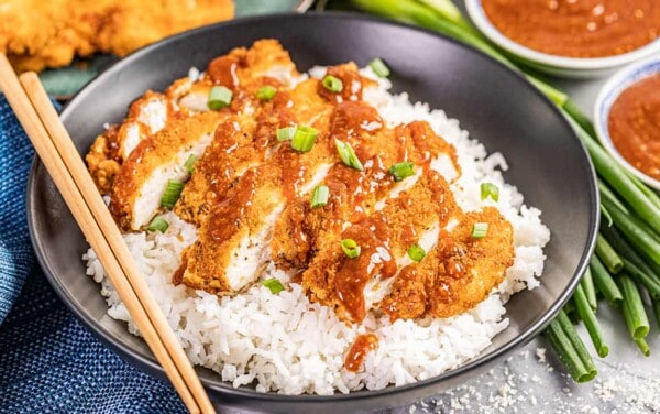 Chicken katsu in a bowl with white rice.