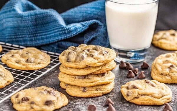 A stack of chocolate chip cookies next to a glass of milk.