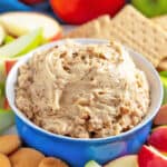 Toffee Apple Dip in a blue bowl surrounded by sliced apples, graham crackers, and Nilla wafers.