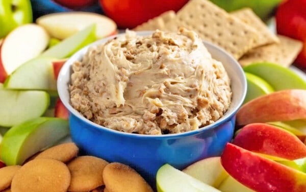 Toffee Apple Dip in a blue bowl surrounded by sliced apples, graham crackers, and Nilla wafers.