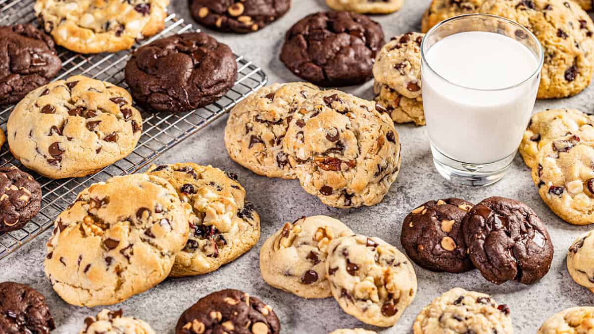 Bakery style cookies on a counter with a glass of milk.