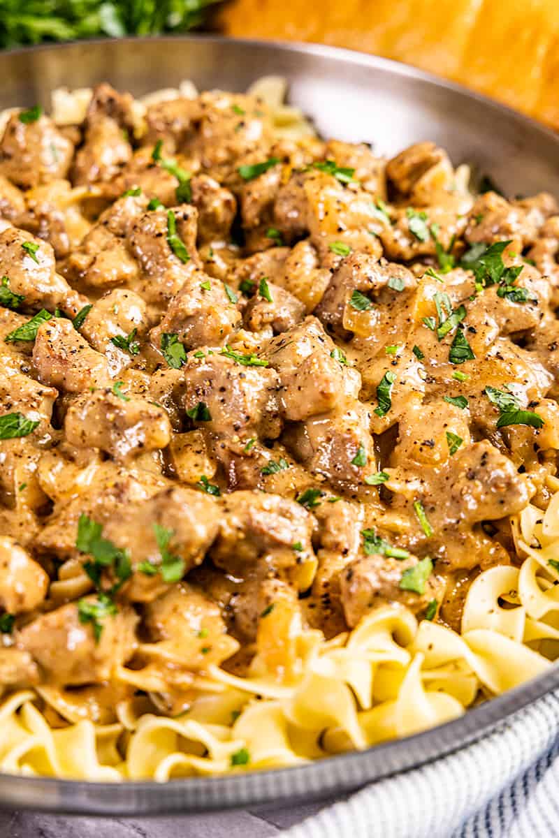 Beef and noodles with freshly chopped parsley on top.