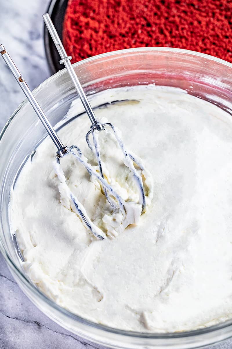 Top view of a glass bowl filled with ermine glaze with a whisk in it.