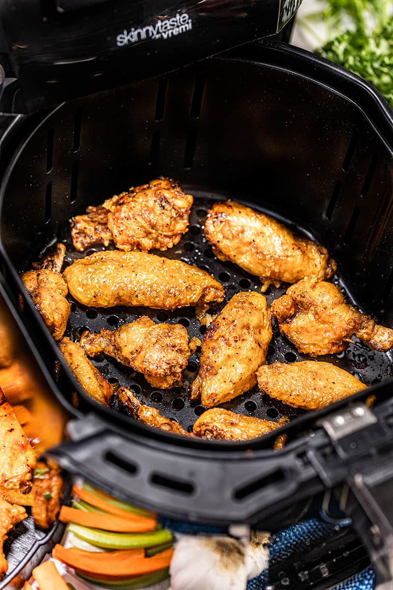 An air fryer basket with chicken wings.