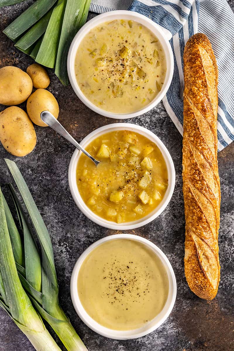 Overhead view of a potato leek soup in bowls and a baguette.