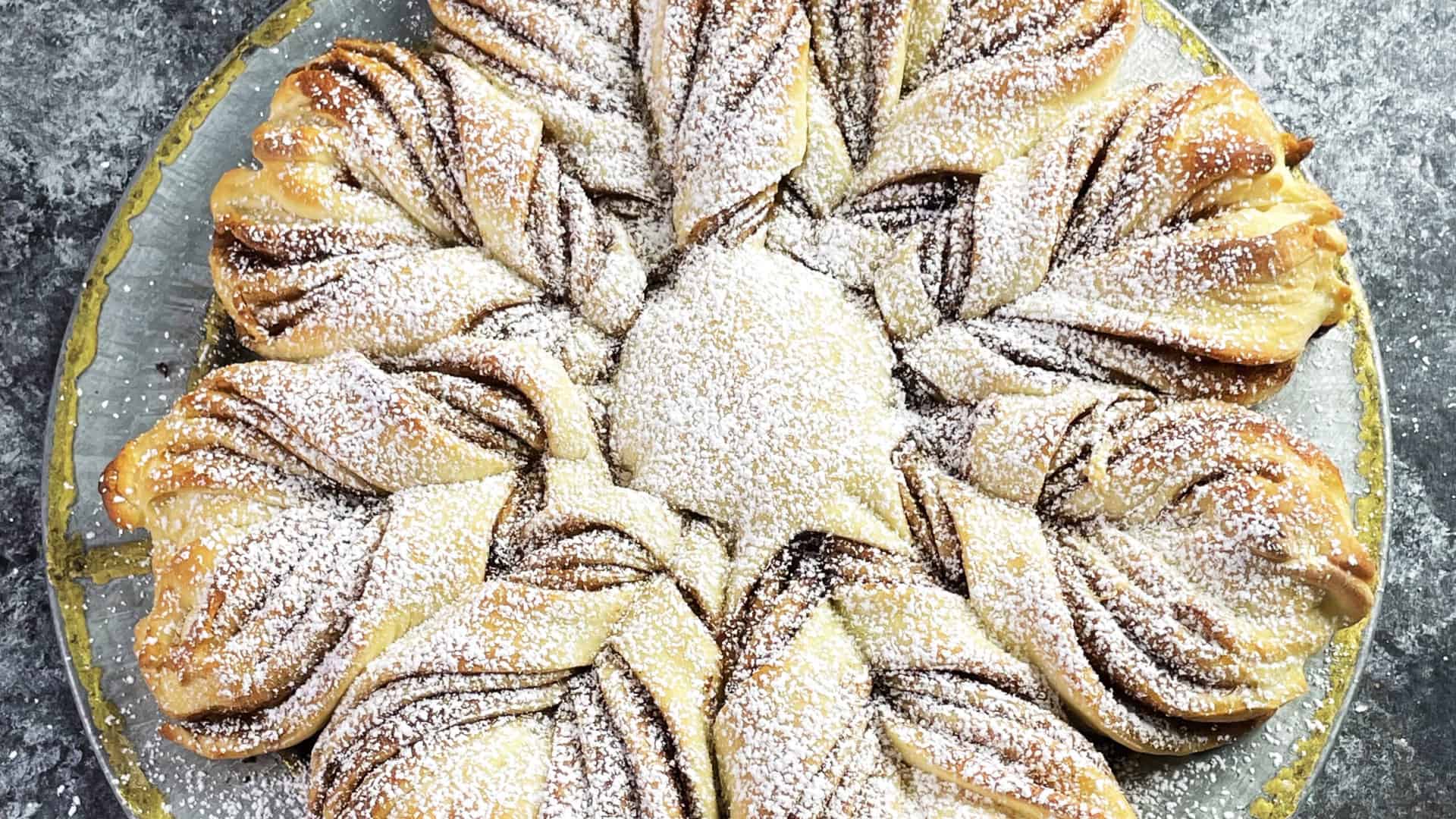 Cinnamon Star bread on a platter dusted in powdered sugar.