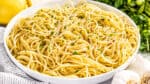 Large white serving bowl filled with olive oil pasta.