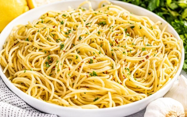 Large white serving bowl filled with olive oil pasta.