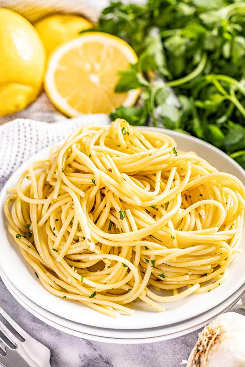 Olive oil pasta on a stack of white plates.