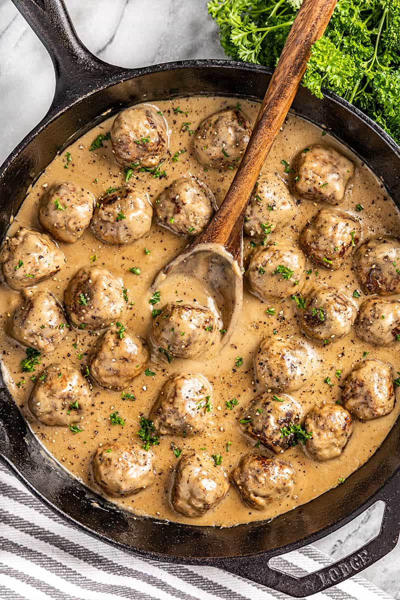 Overhead view of a cast iron skillet filled with Swedish meatballs and gravy.