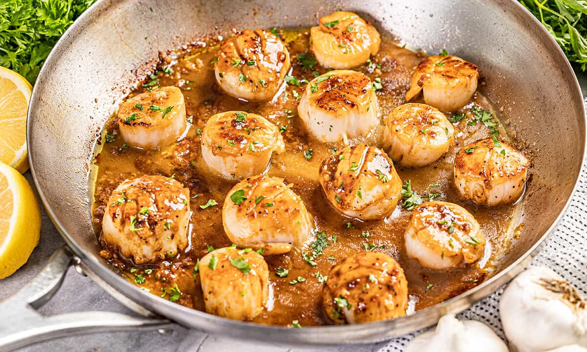 Cooked scallops in a stainless steel skillet.