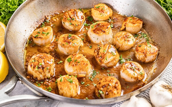 Cooked scallops in a stainless steel skillet.