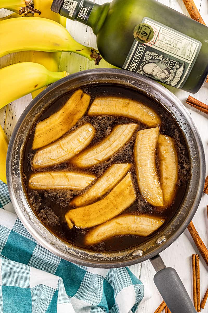 Overhead view of bananas foster in a stainless steel skillet.