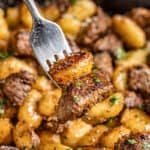 A fork filled with gnocchi and steak bites.