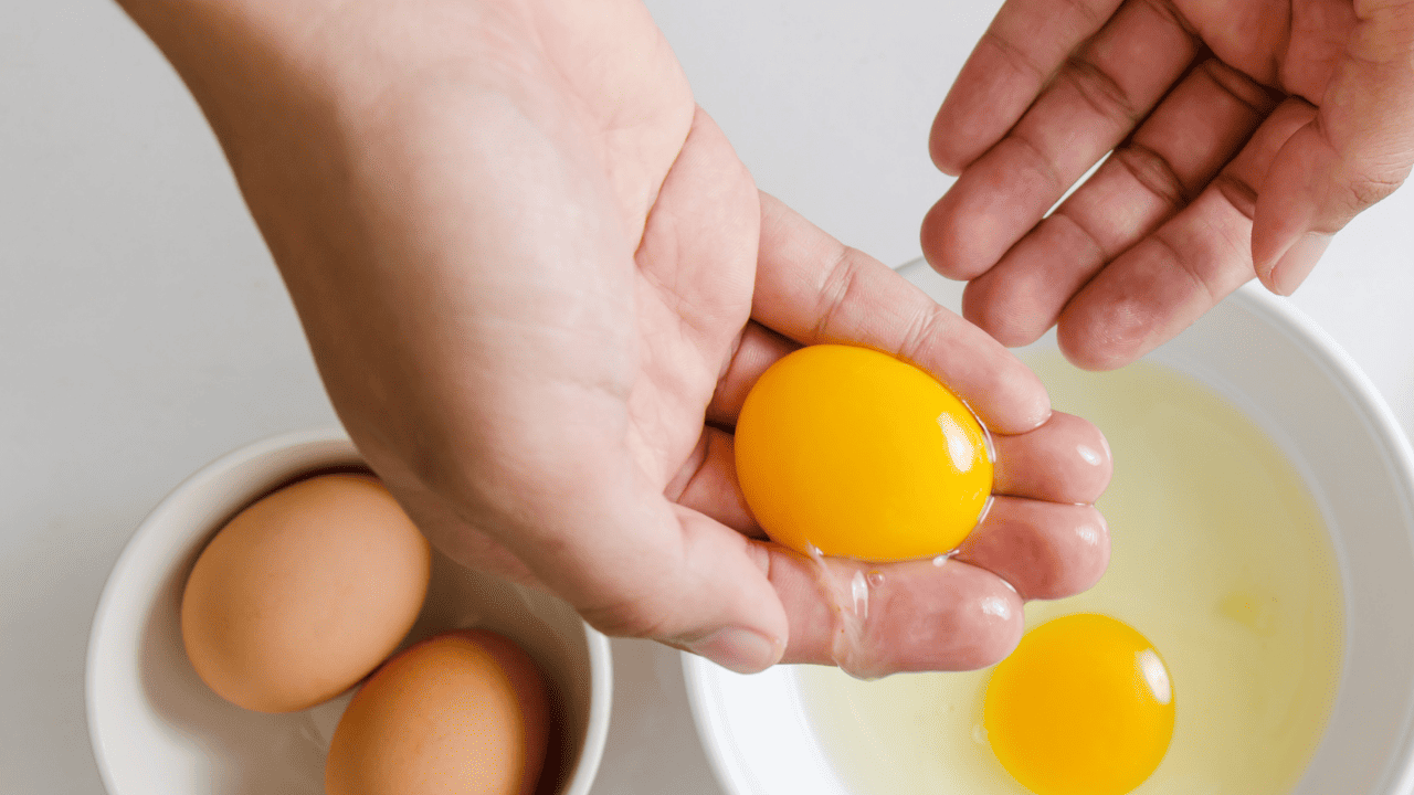 A hand holding an egg yolk.