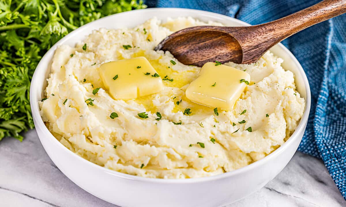 A large bowl of creamy mashed potatoes with butter on top.