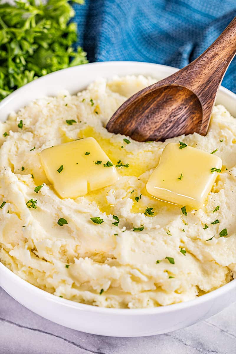 Creamy mashed potatoes in a bowl with butter on top.