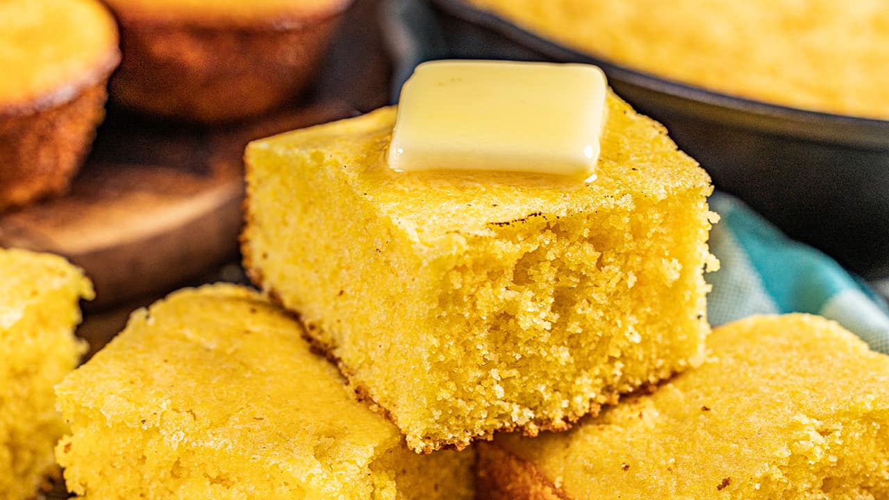A slice of buttermilk cornbread with a pat of butter on top.