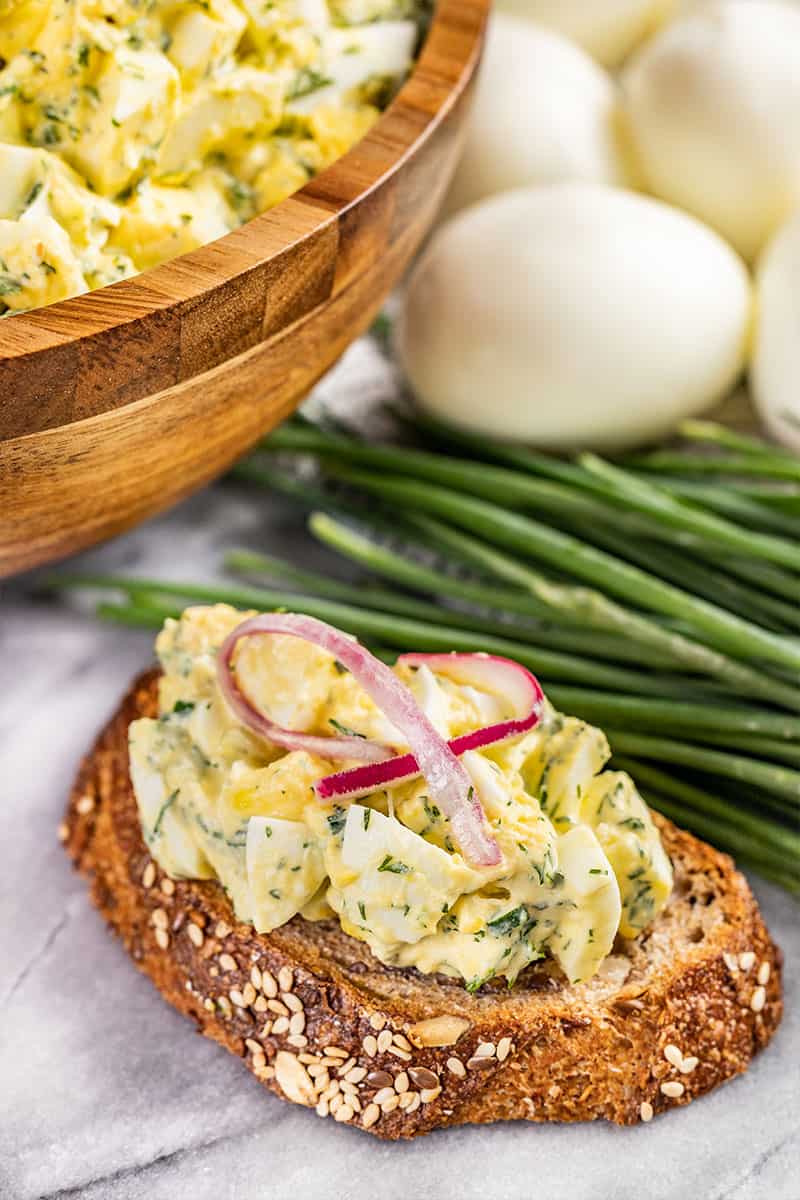 Close up view of egg salad on a piece of whole grain bread.