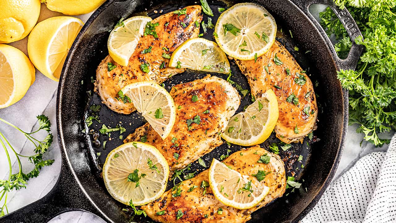 Overhead view looking into a cast iron skillet with chicken breasts.