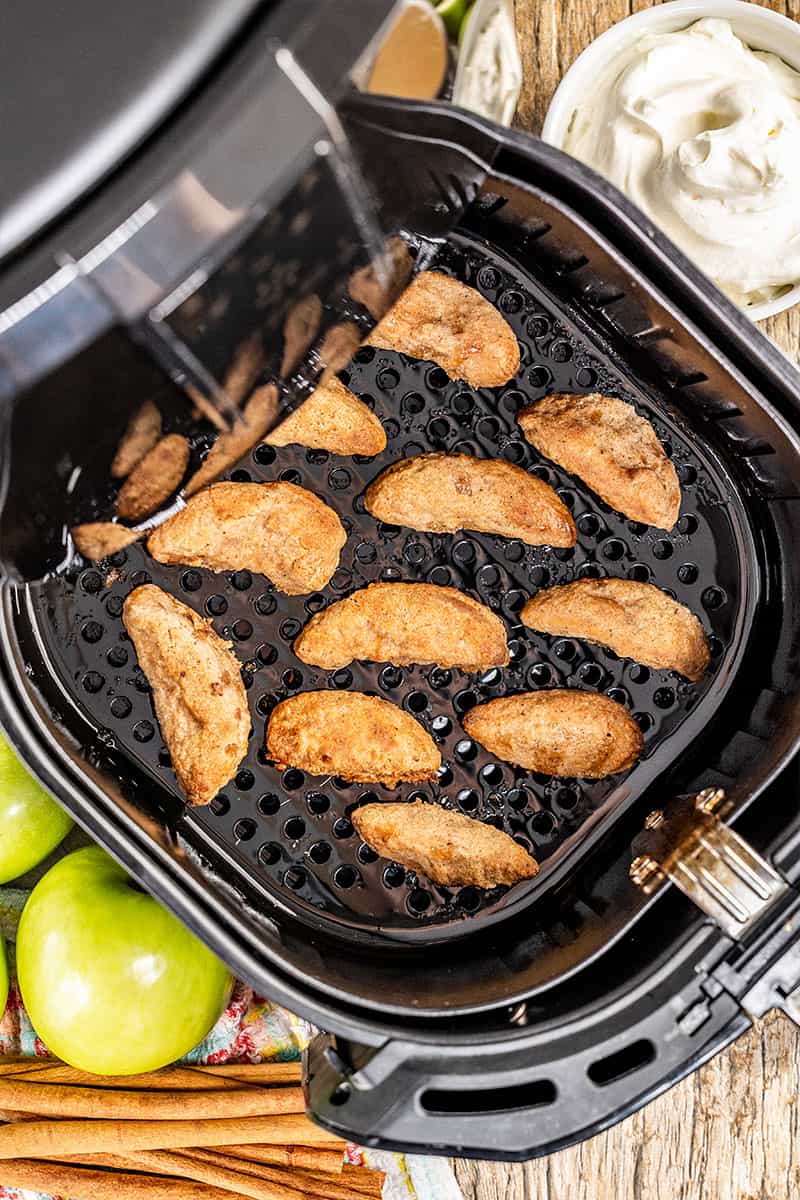 Overhead view of apple fries in an air fryer.