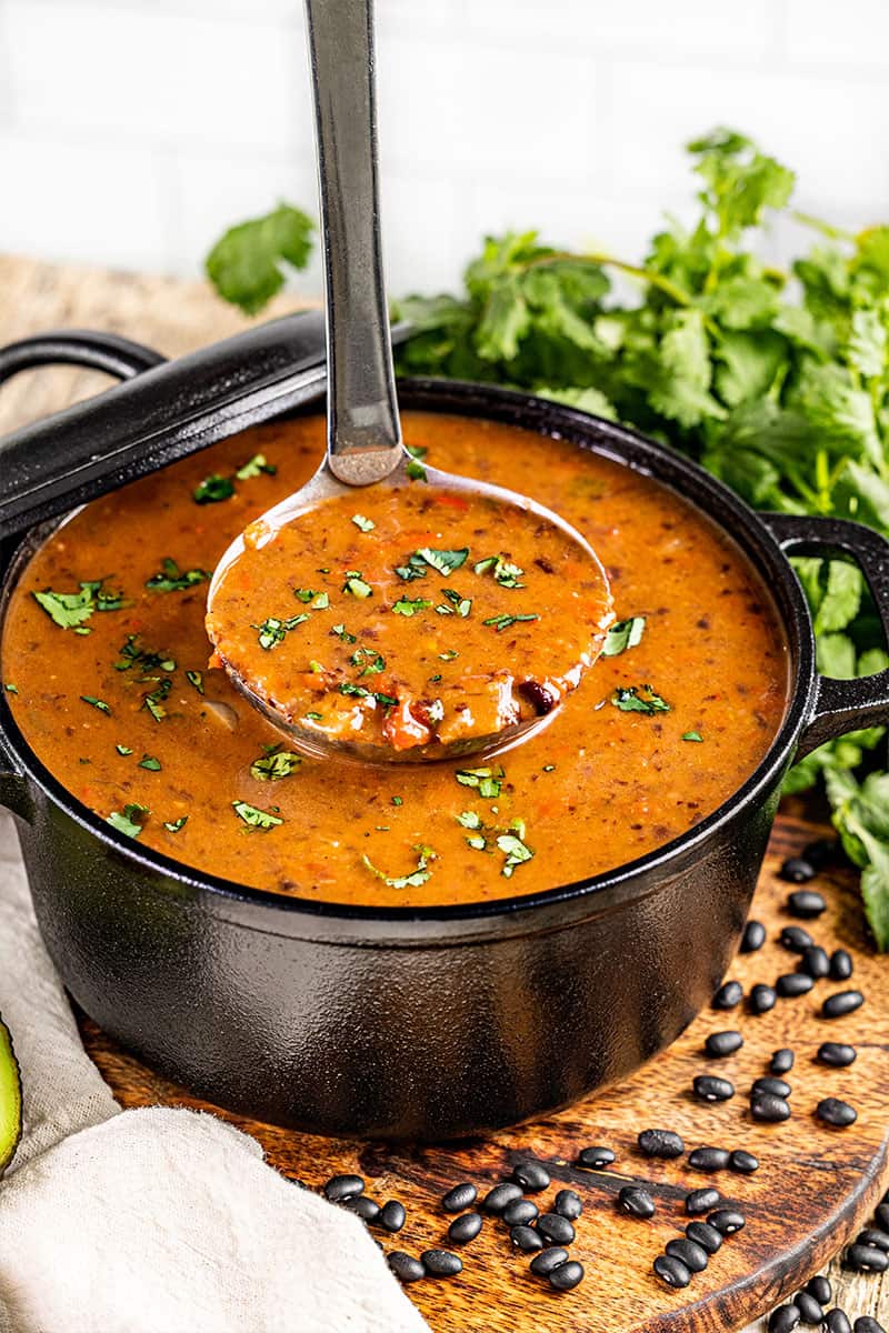 A large pot of black bean soup with a ladle.