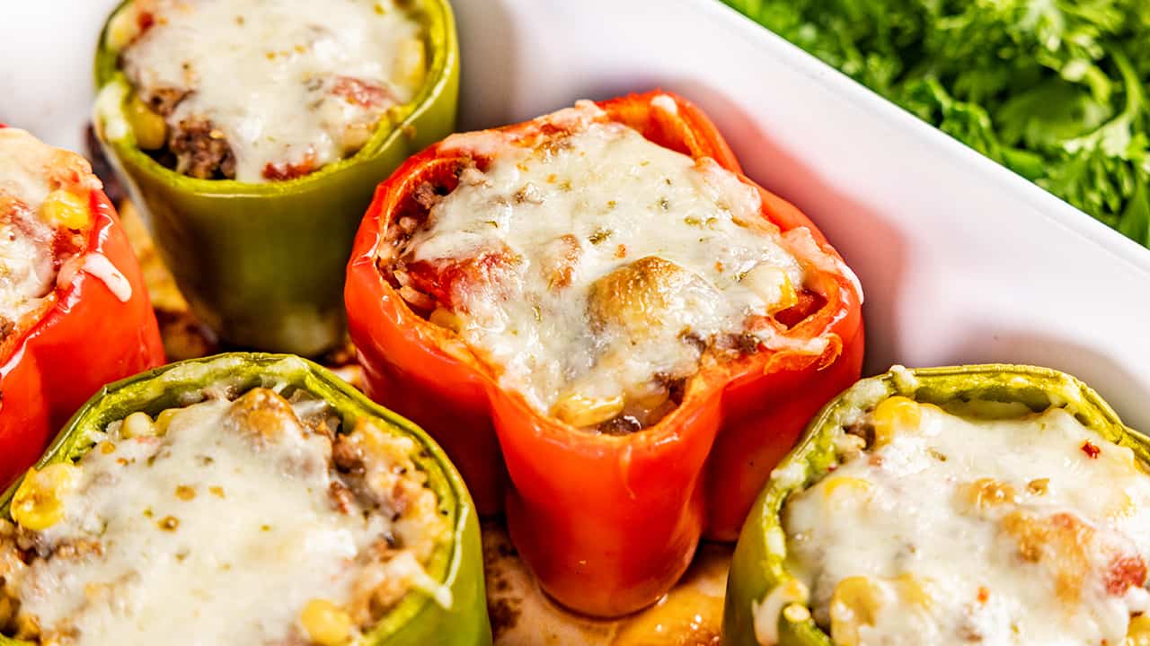 Close up view of stuffed bell peppers in a baking dish.