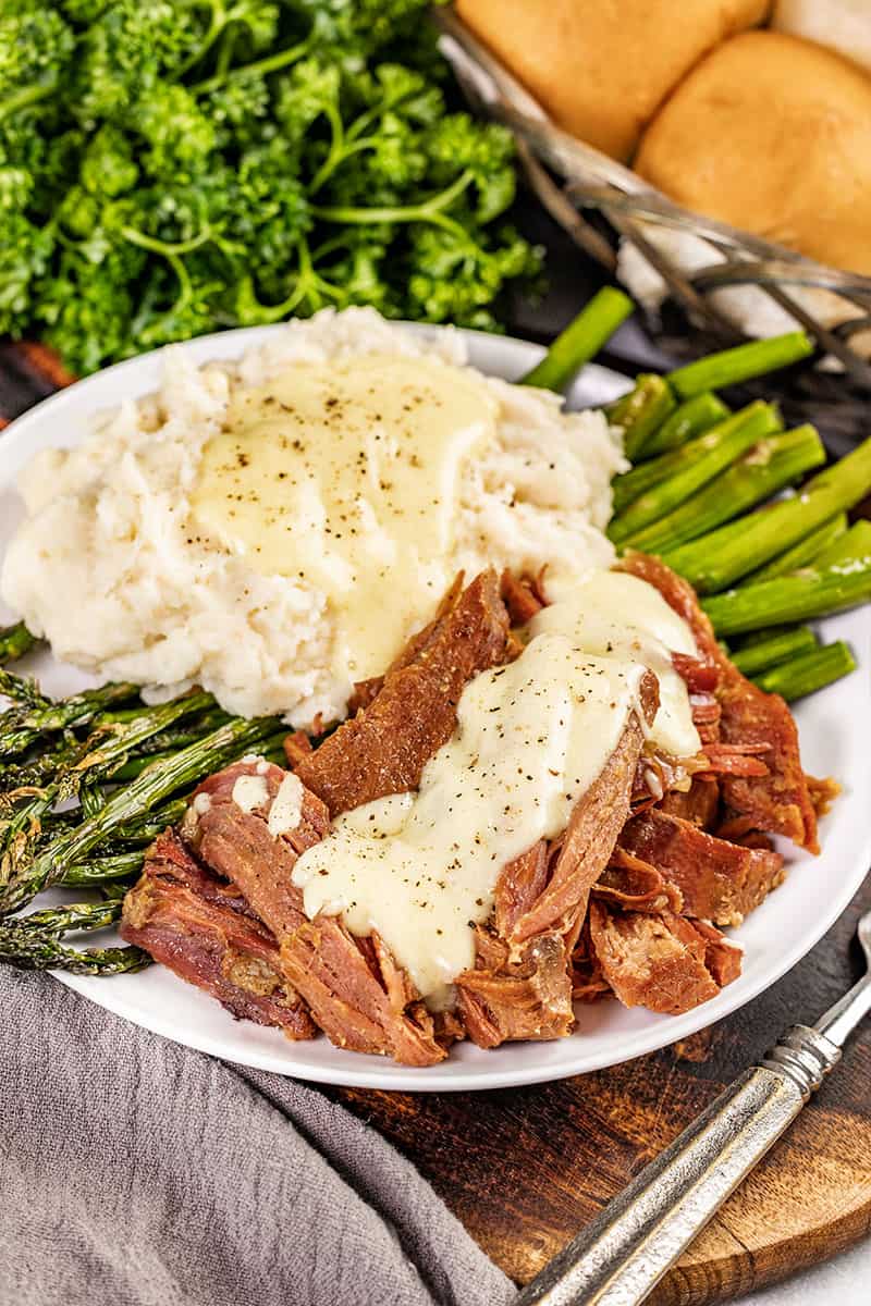 Pulled ham with gravy on top on a dinner plate.