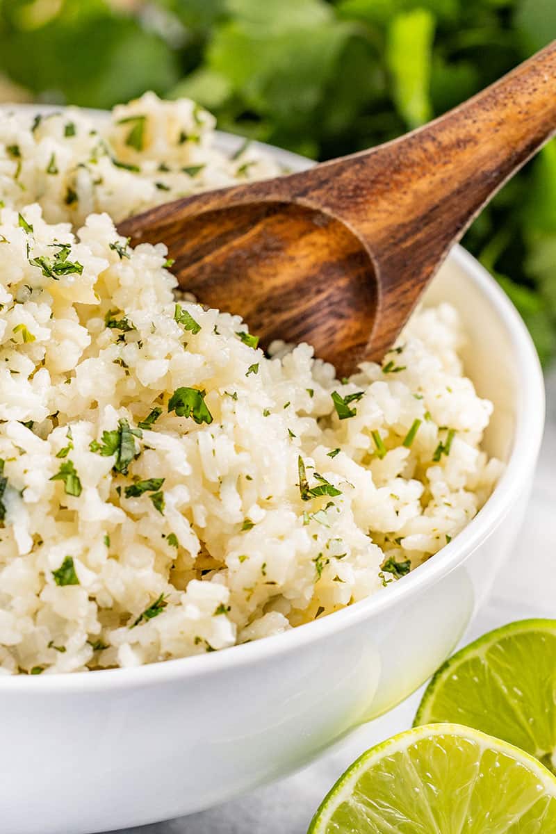 Close up view of cilantro lime rice with a wooden spoon.