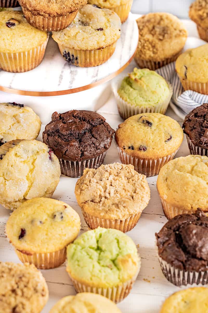 A lot of different flavored muffins on a counter.