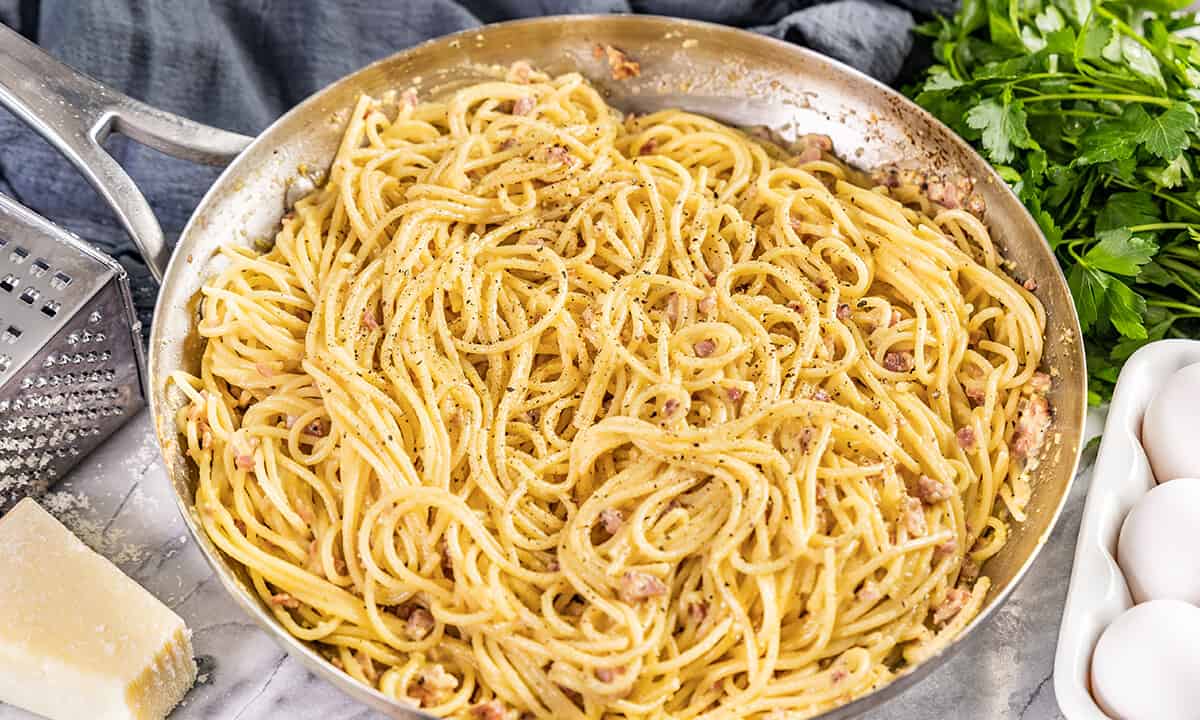 A close up view of a skillet full of pasta carbonara.