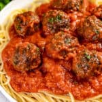 Close up view of baked meatballs on spaghetti.