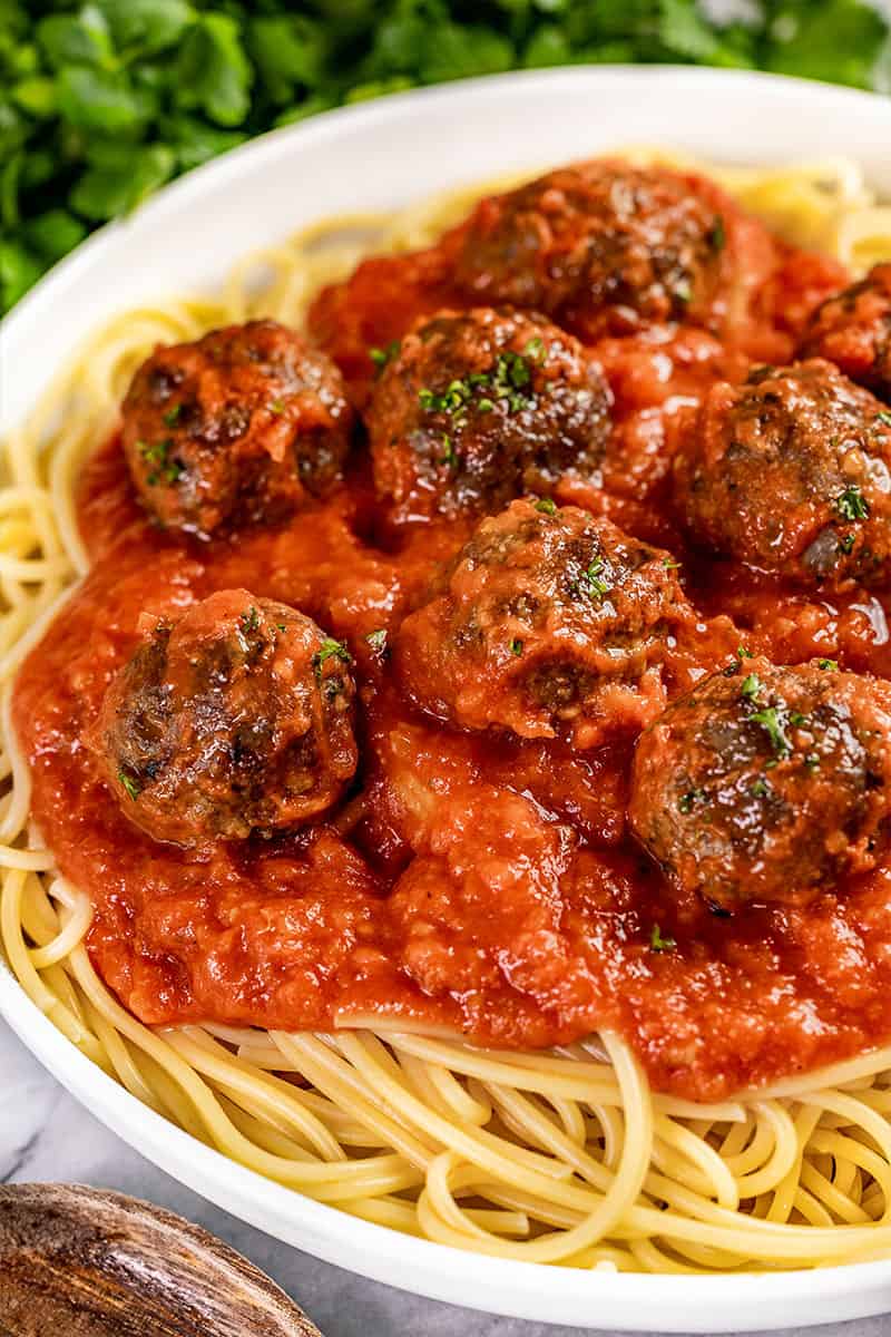 Close up view of baked meatballs on spaghetti.