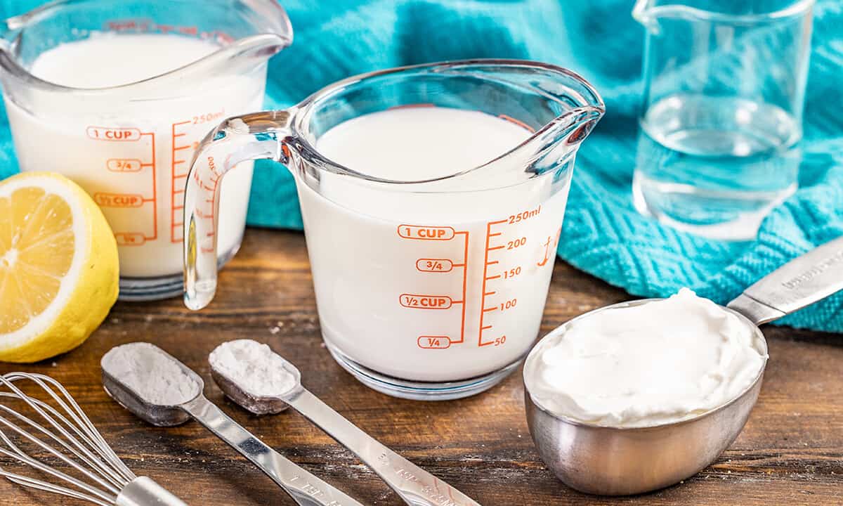 A glass measuring jar filled with milk to make homemade buttermilk.
