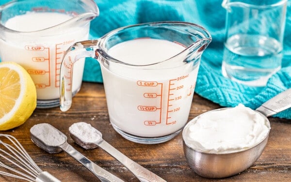 A glass measuring jar filled with milk to make homemade buttermilk.