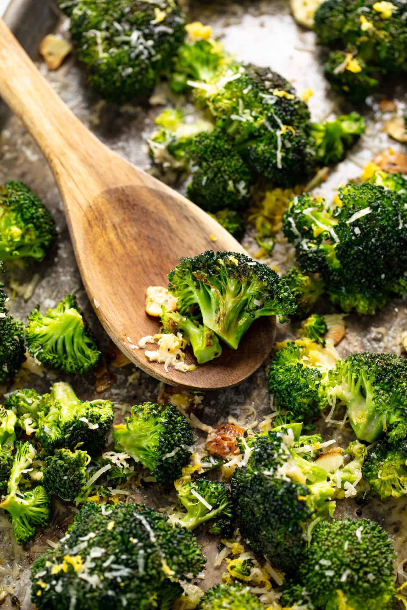 A wooden spoon with roasted broccoli.