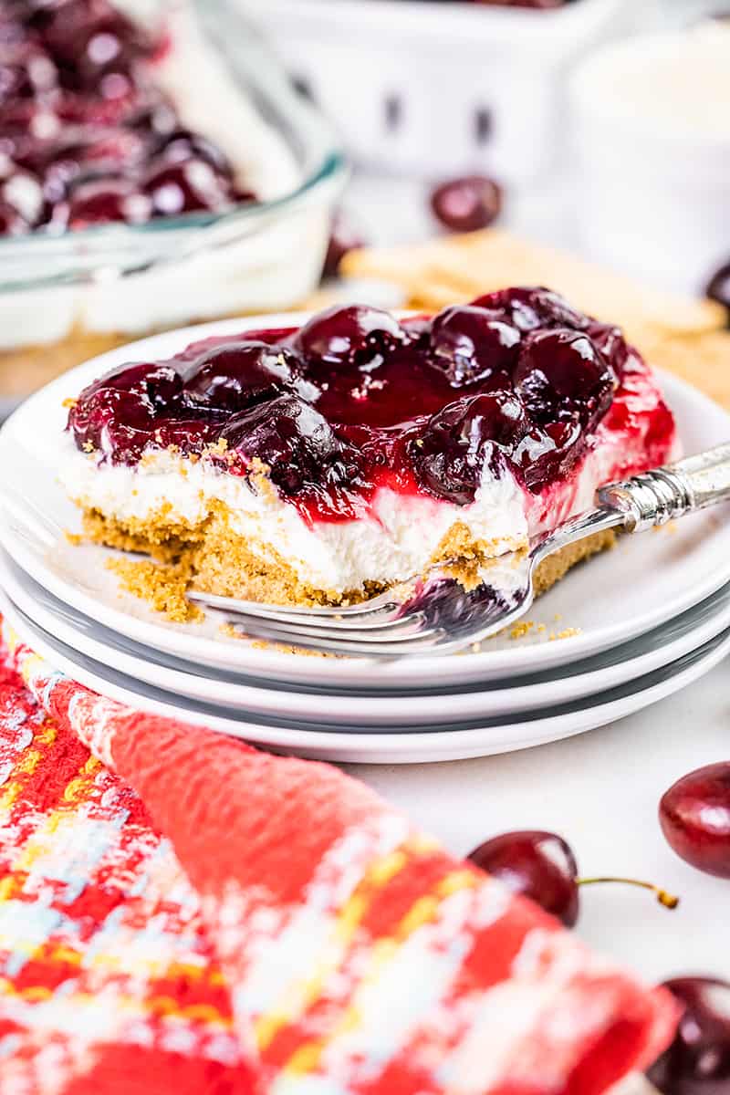 Close up view of a slice of cherry delight with a bite taken out.