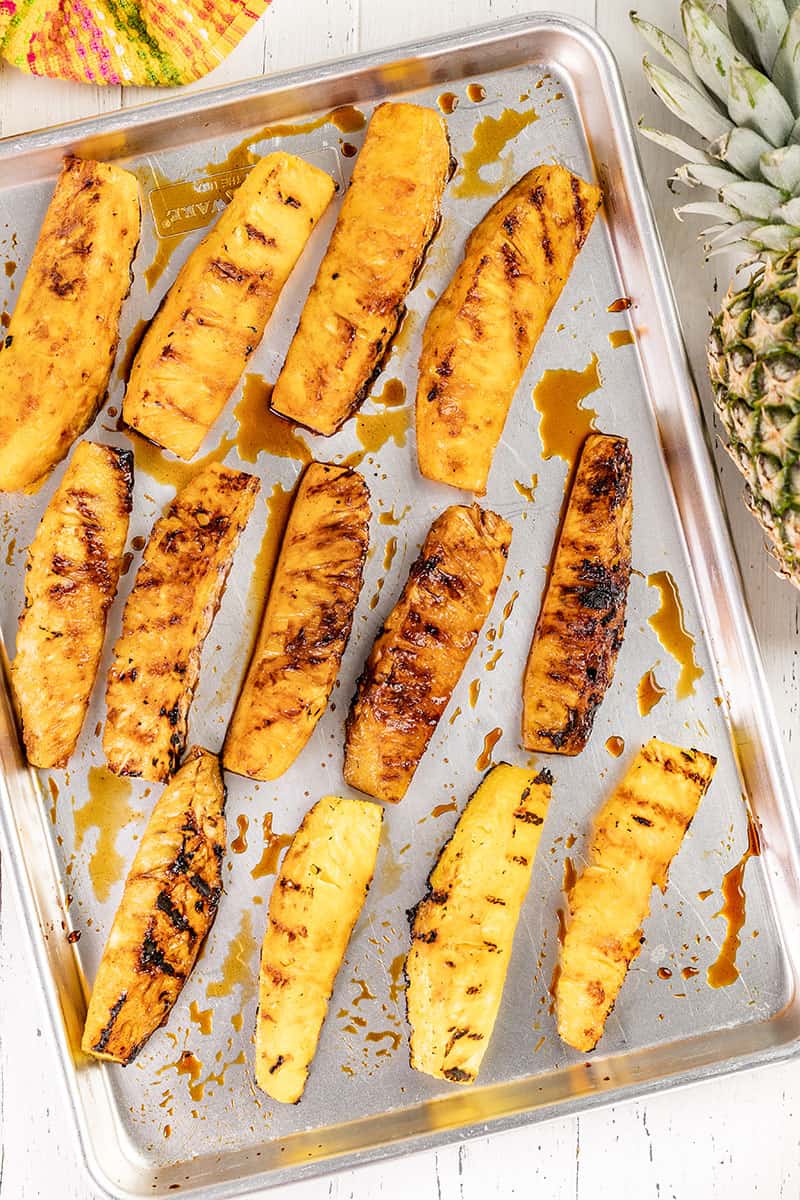 Grilled pineapple spears on a baking tray.
