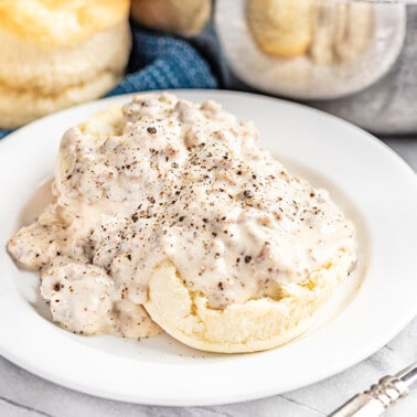 Biscuits and sausage gravy on a white plate.