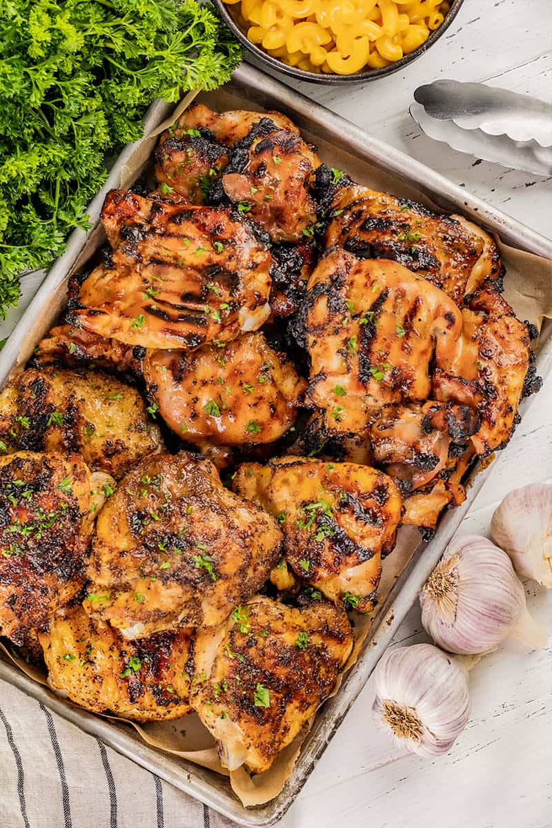 Overhead view of grilled chicken thighs on a baking sheet.