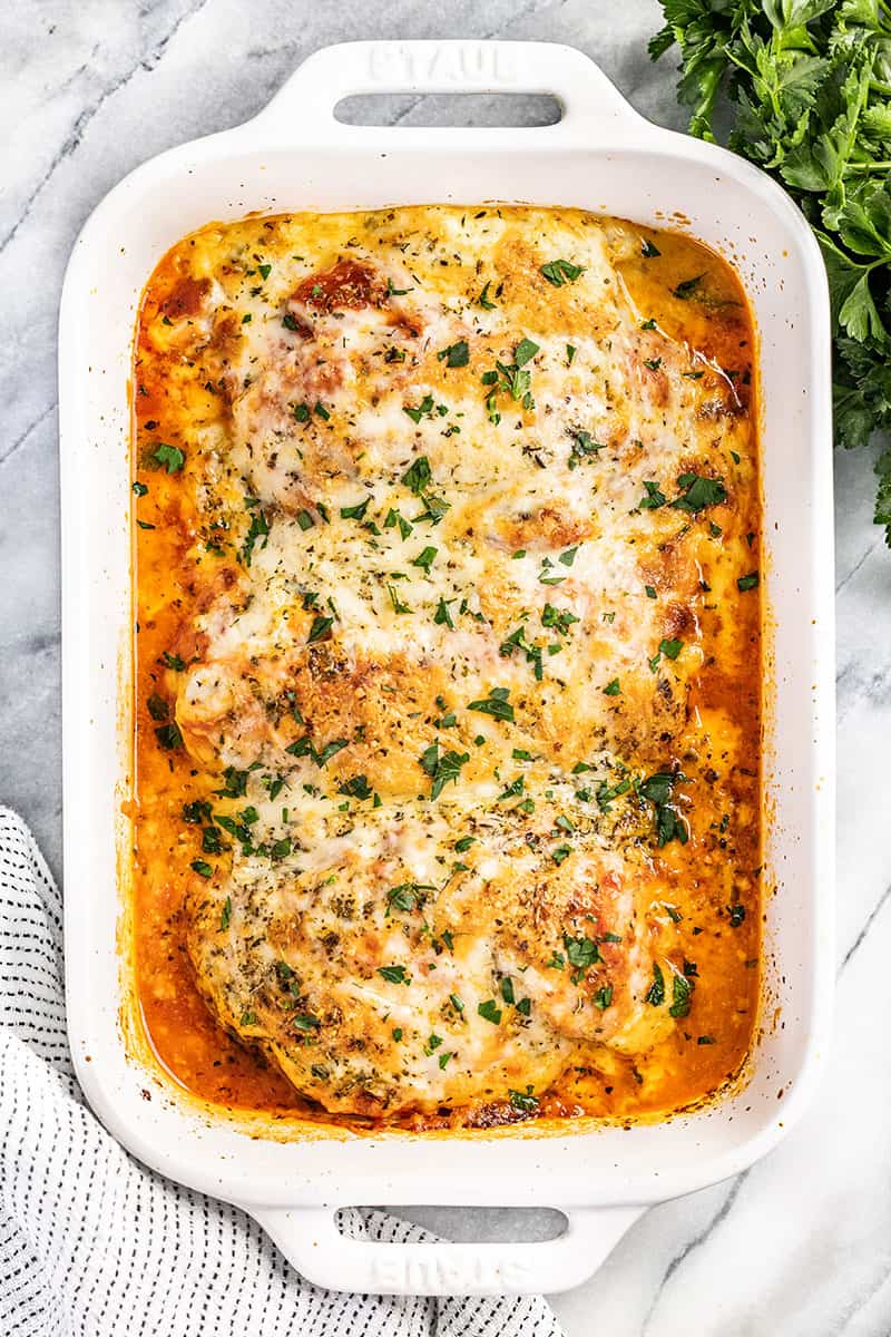 An overhead view of lasagna stuffed chicken breasts in a casserole dish.