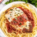 Chicken parmesan and spaghetti on a dinner plate.