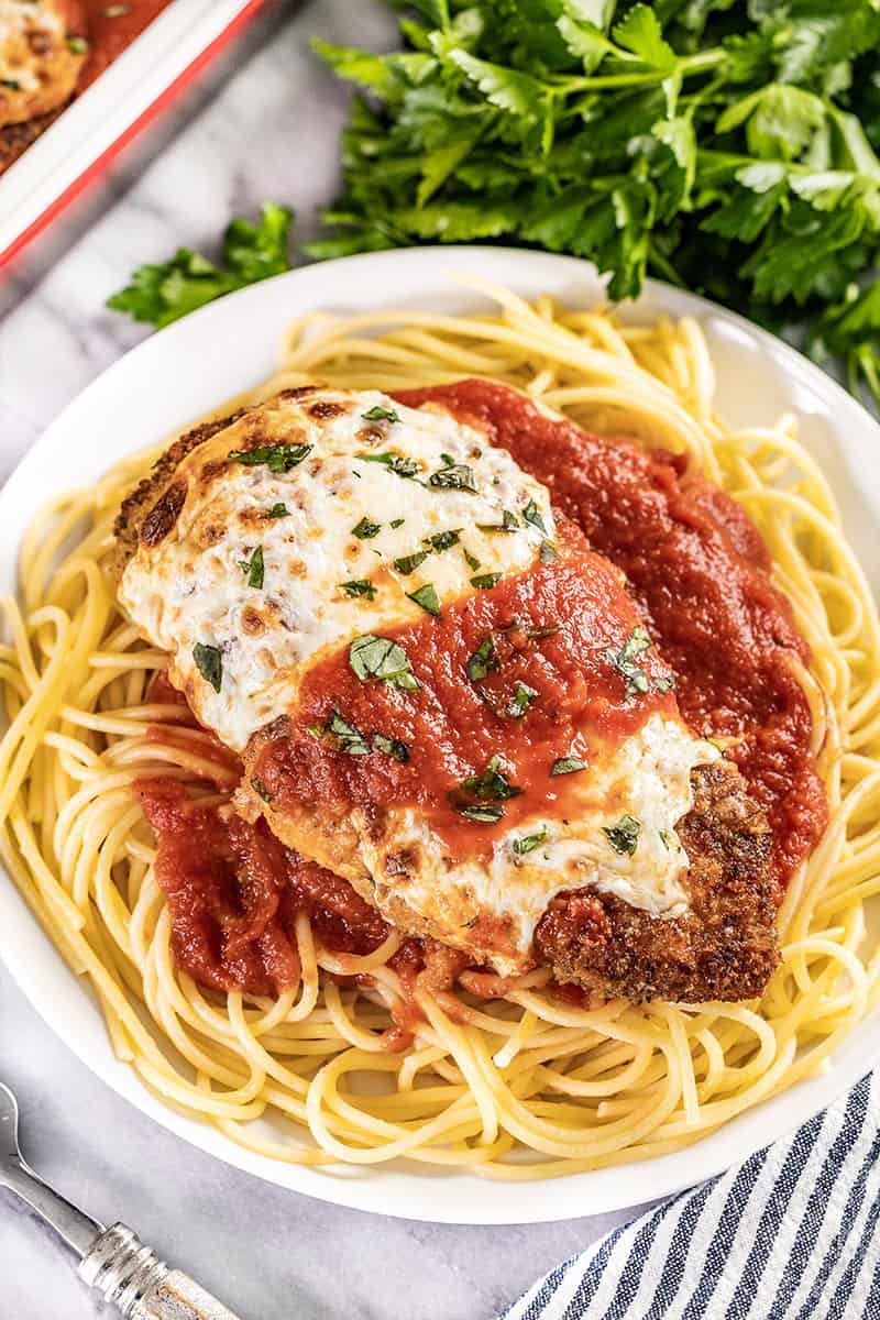 Chicken parmesan and spaghetti on a dinner plate.