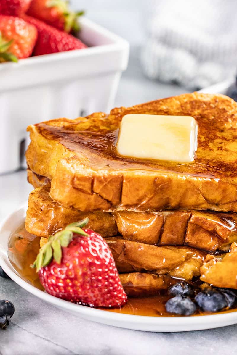 French toast stacked on a plate with strawberries.