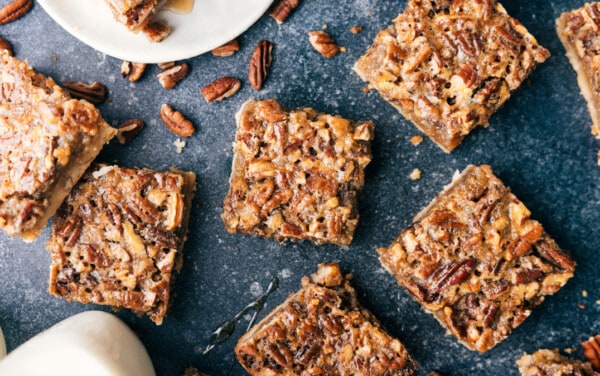 Individual servings of pecan bars scattered out over a black granite counter.