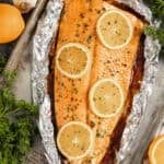 Overhead view of a whole salmon fillet with orange slices on top.